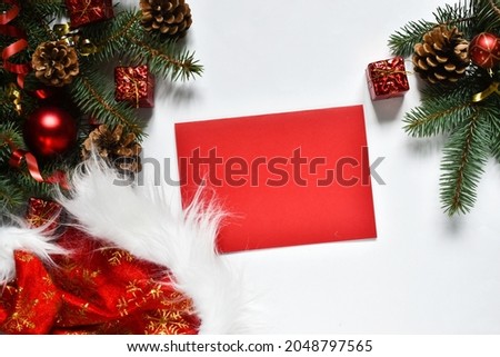 Christmas flat lay white background with fir tree branches and red decorations, fir cones, santa claus hat and red paper for Free space for design. Holiday concept. Greeting card