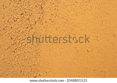A peeling layer of orange paint on the wall. Background with peeling orange paint