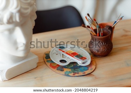 Plaster head on a wooden table. Plaster bust in an art studio. Drawing lessons. Art school concept. Royalty-Free Stock Photo #2048804219