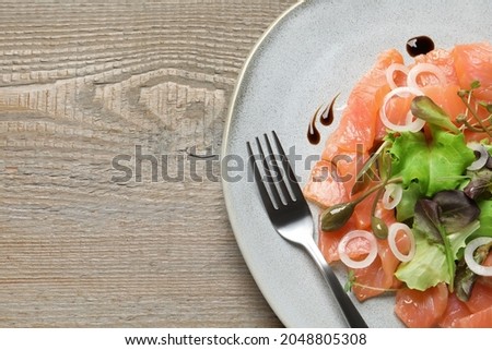 Delicious salmon carpaccio served on wooden table, top view. Space for text