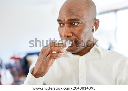 African man gives a saliva sample for the coronavirus rapid test as a self-test at home Royalty-Free Stock Photo #2048814395