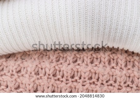 Two different knitted sweaters textures. White and pink colors. Warm cozy clothing for an autumn and winter time.