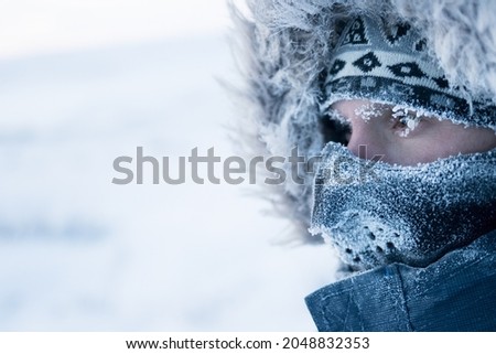 A man in winter clothes and a mask. Portrait of a traveler in the Arctic. Ice and snow on eyelashes, face and mask. Cold polar climate. Extreme travel and expeditions to the far North to the Arctic. Royalty-Free Stock Photo #2048832353