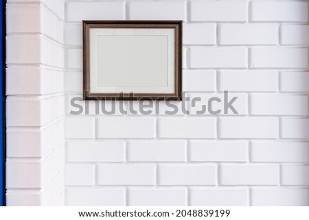Empty picture frame on a white brick wall.