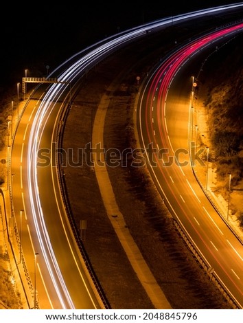 Top view of a highway where, with a long exposure, the wakes of cars speeding by are captured in the image.