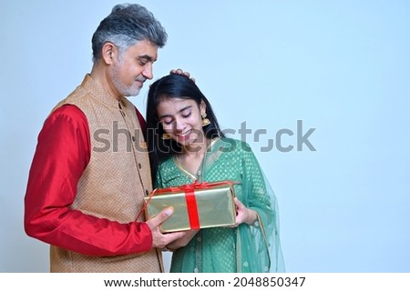 Father with daughter in tradional clothes holding gift box in hand  Royalty-Free Stock Photo #2048850347