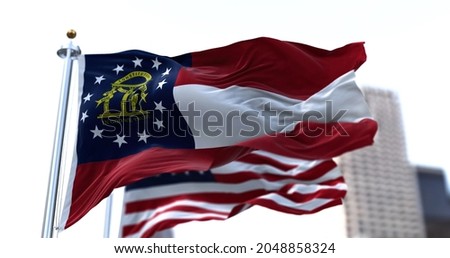 the flag of the US state of Georgia waving in the wind with the American stars and stripes flag blurred in the background. On January 2, 1788, Georgia became the fourth state to join the Union