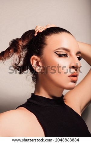 woman with dark hair and makeup pinning her hair