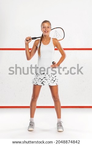Squash player on a squash court with racket. White sportswear. Beautiful girl teenager and athlete with racket on court. Sport concept. Royalty-Free Stock Photo #2048874842