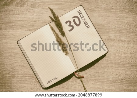 december 30. 30th day of month, calendar date.Blank pages of notebook are beige, with dried spikelets. Concept of day of year, time planner, winter month