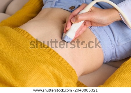 Unrecognizable sonographer doing ultrasound diagnostic of gallbladder, pancreas, right lobe, liver, bile ducts and abdominal cavity with convex probe sensor. Doctor home visit. Linear probe sonogram Royalty-Free Stock Photo #2048885321