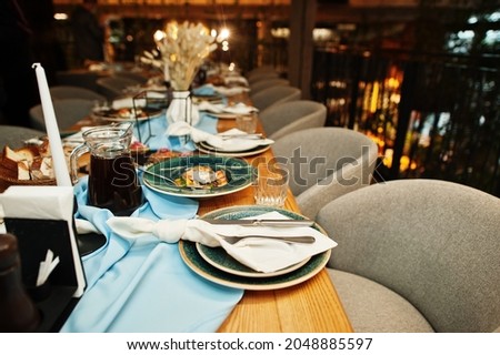 Beautifully laid tables with food, glasses and appliances in restaurant.