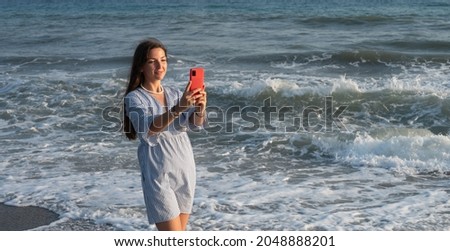 Young woman with phone by the sea.