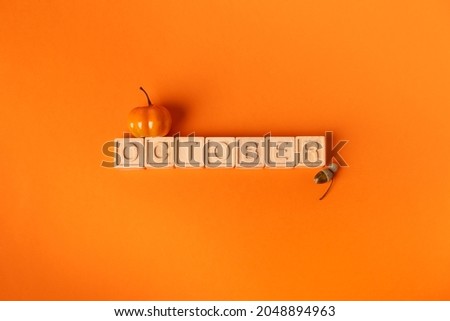October word on wooden blocks and small pumpkin and acorn . Orange background

