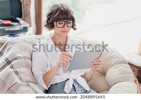 Photo of minded young focused woman hold hand tablet pen work remote indoors inside house home apartment