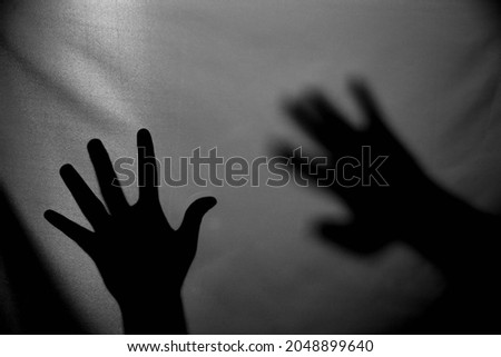 The concept of the shadow of hand behind the fabric illuminated from behind. Halloween background.