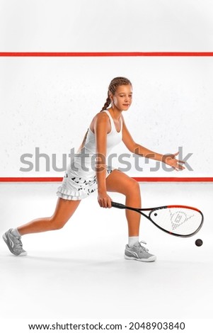Squash player on a squash court with racket. White sportswear. Beautiful girl teenager and athlete with racket on court. Sport concept. Royalty-Free Stock Photo #2048903840