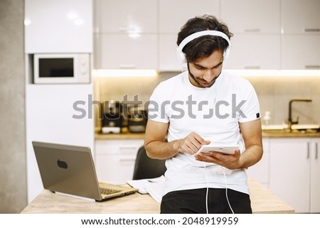 Online education. Young arabic man study with a laptop at home and taking notes.