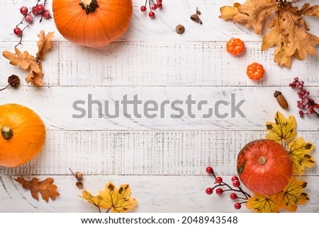 Decor from pumpkins, berries and leaves on white rustic wooden background. Concept of Thanksgiving day or Halloween. Top view festive autumn composition with copy space.