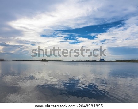 Beautiful mirror reflection blue skies and cloud on calm water surface, shoot in the morning, empry space, holiday, vacation, freedom scene with horizon