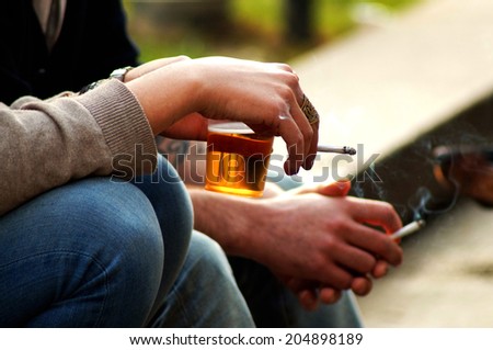 smoke and beer . The hands of people who maintain a beer and a cigarette Royalty-Free Stock Photo #204898189