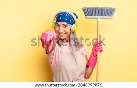 middle age pretty woman pointing at camera choosing you. household and broom concept