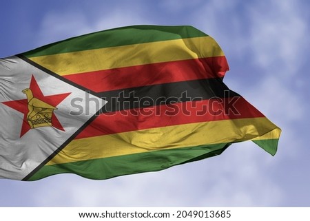 Zimbabwe flag isolated on the blue sky with clipping path. close up waving flag of Zimbabwe. flag symbols of Zimbabwean.