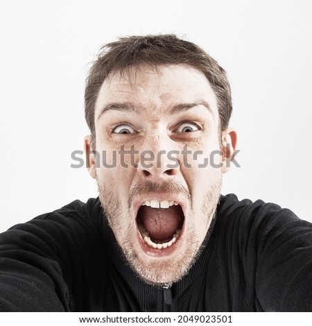 unshaven man in black jacket shouts with on white background