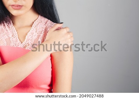 woman has shoulder pain on gray background