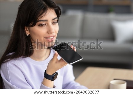 Voice Search Concept. Closeup portrait of young woman using virtual assistant or calling on smartphone at home, blurred background, free copy space. Smiling lady talking on cell phone, sending message