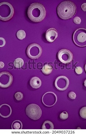 Onions, Contemporary lay flat of cut purple onion rings of different sizes on a deep purple solid background 