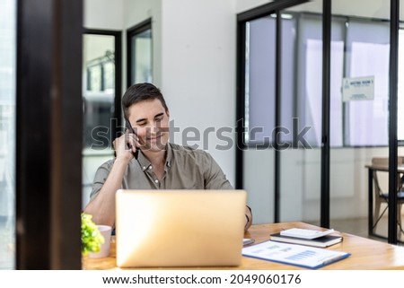 Man talking on the phone in the office, He is a businessman executive of a startup company founded with partners, He is a young and energetic executive and the company's earnings continue to grow.