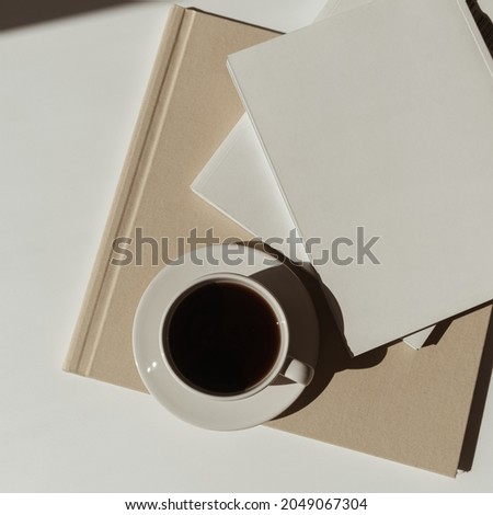 Home office workspace with notebook sheet, coffee cup, marble tray in sunlight shadows. Aesthetic luxury bohemian minimal lady boss business lifestyle concept. Flat lay, top view