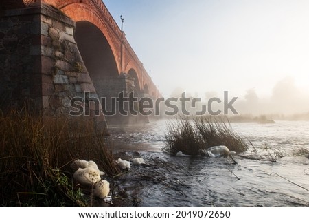 Long red brick bridge in foggy, sunny morning, Kuldiga, Latvia.