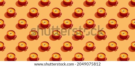 Autumn pumpkins soup in red orange bowl or cup on orange background, modern concept, seamless pattern, banner