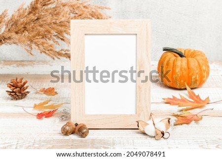 Blank photo frame with pumpkin and autumn decorations at the background.