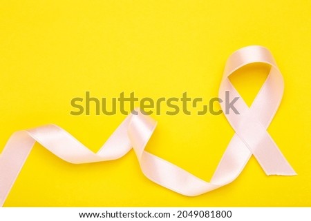 Cancer concept. Pink ribbon on yellow background