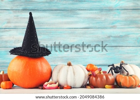 Halloween pumpkins, candies, black hat and spider on blue background