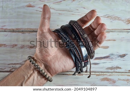 Stylish man wears wrist wooden and leather bracelets Royalty-Free Stock Photo #2049104897