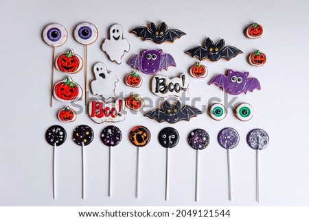 Sweet treats for Halloween on white isolated background. Homemade cakes of cute ghosts, orange pumpkins, lollipops, funny black bats, gingerbread cookies of scary eyes. Childrens food for the holiday
