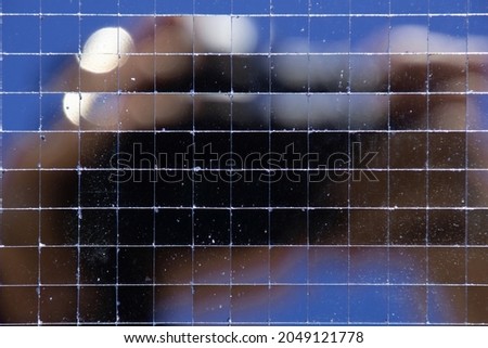 Photographer with camera reflected blurred in a mosaic mirror tiles background