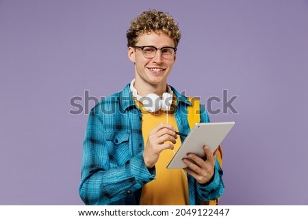 Young cool boy teen student in casual clothes backpack headphones glasses use work on tablet pc computer isolated on plain violet background studio. Education in high school university college concept Royalty-Free Stock Photo #2049122447