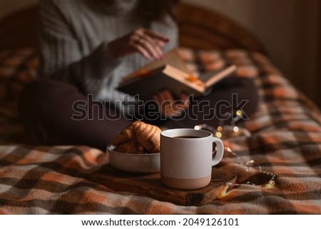 cozy autumn evening: girl, coffee, book and croissants Royalty-Free Stock Photo #2049126101
