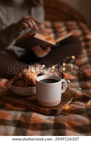 cozy autumn evening: girl, coffee, book and croissants Royalty-Free Stock Photo #2049126107