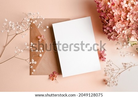 Invitation or greeting card mockup with envelope and hydrangea and gypsophila flowers decorations. Royalty-Free Stock Photo #2049128075