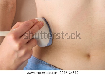 Closeup of anonymous doctor doing ultrasound diagnostics of patient right kidney prolapse. Scanning with convex probe sensor. Abdominal cavity examination. Sonography appointment Royalty-Free Stock Photo #2049134810