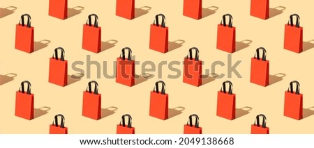 Bright red craft bag with black pattern handles on a beige background. Black friday concept. Big Sale Royalty-Free Stock Photo #2049138668