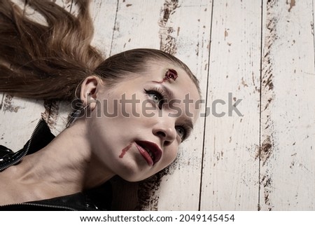 Hit woman. Woman in a latex suit killed in gunfire shot in the head. Royalty-Free Stock Photo #2049145454