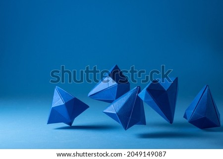 Several geometric diamond-shaped blue colored paper figures on a light blue surface. Elegant background providing concept of parts of a whole, business, team, products, etc.