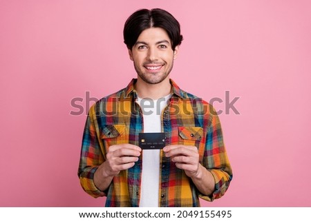 Photo of charismatic pretty young gentleman wear plaid outfit holding credit card smiling isolated pink color background